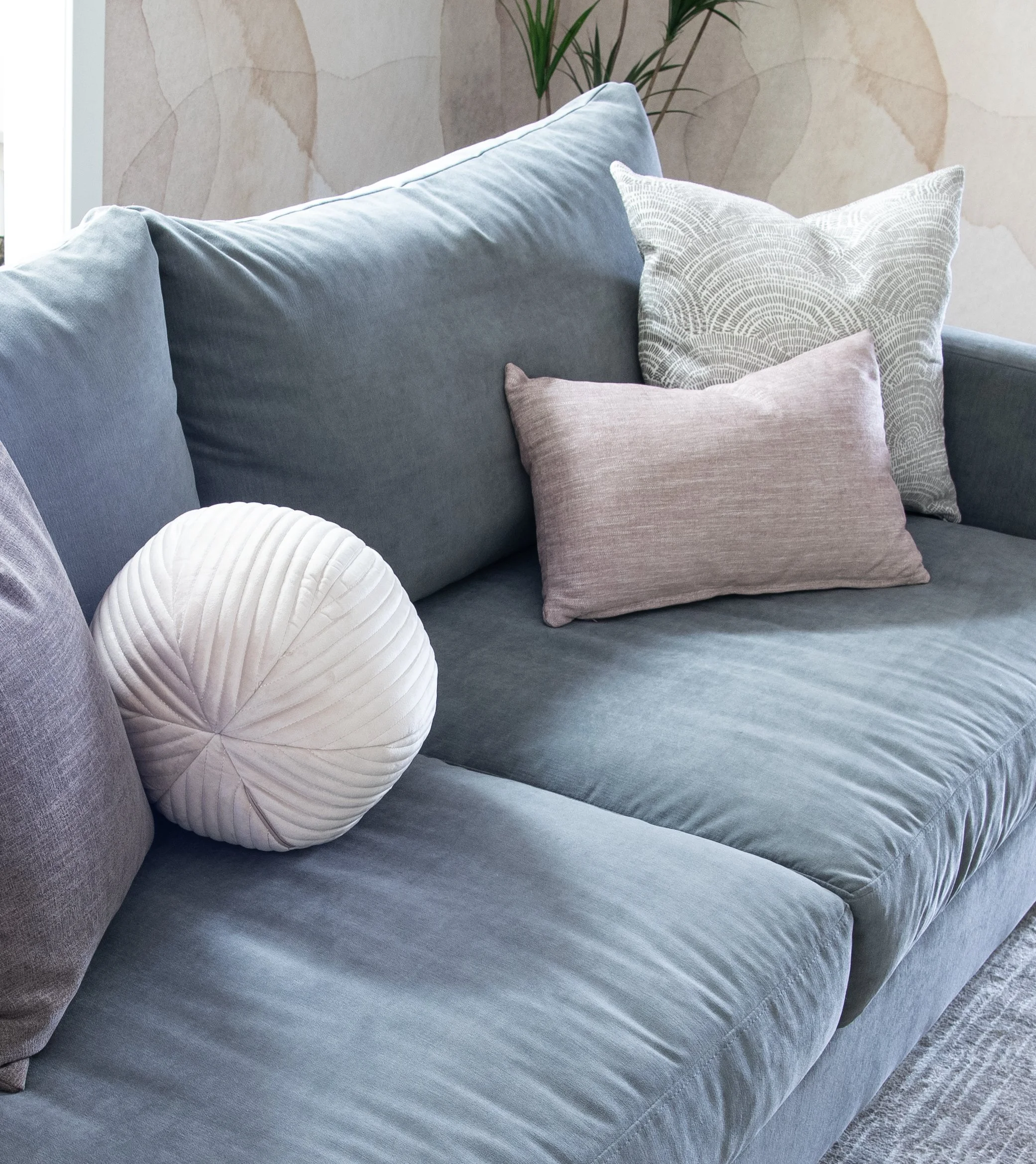 Van Gogh Design's Sooke Aveline Sofa in Breton Storm blue-grey chenille fabric. Cute custom pillows sit on top including a round corduroy toss cushion from Renwil.