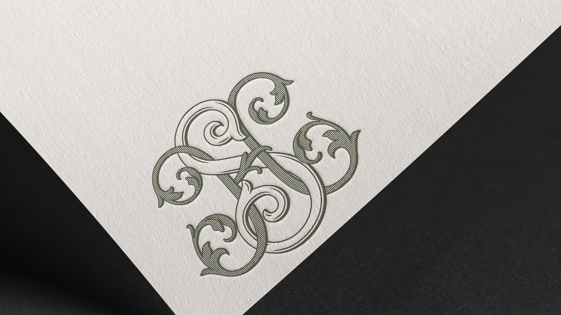 A close-up of a textured paper with an ornate, decorative monogram design.