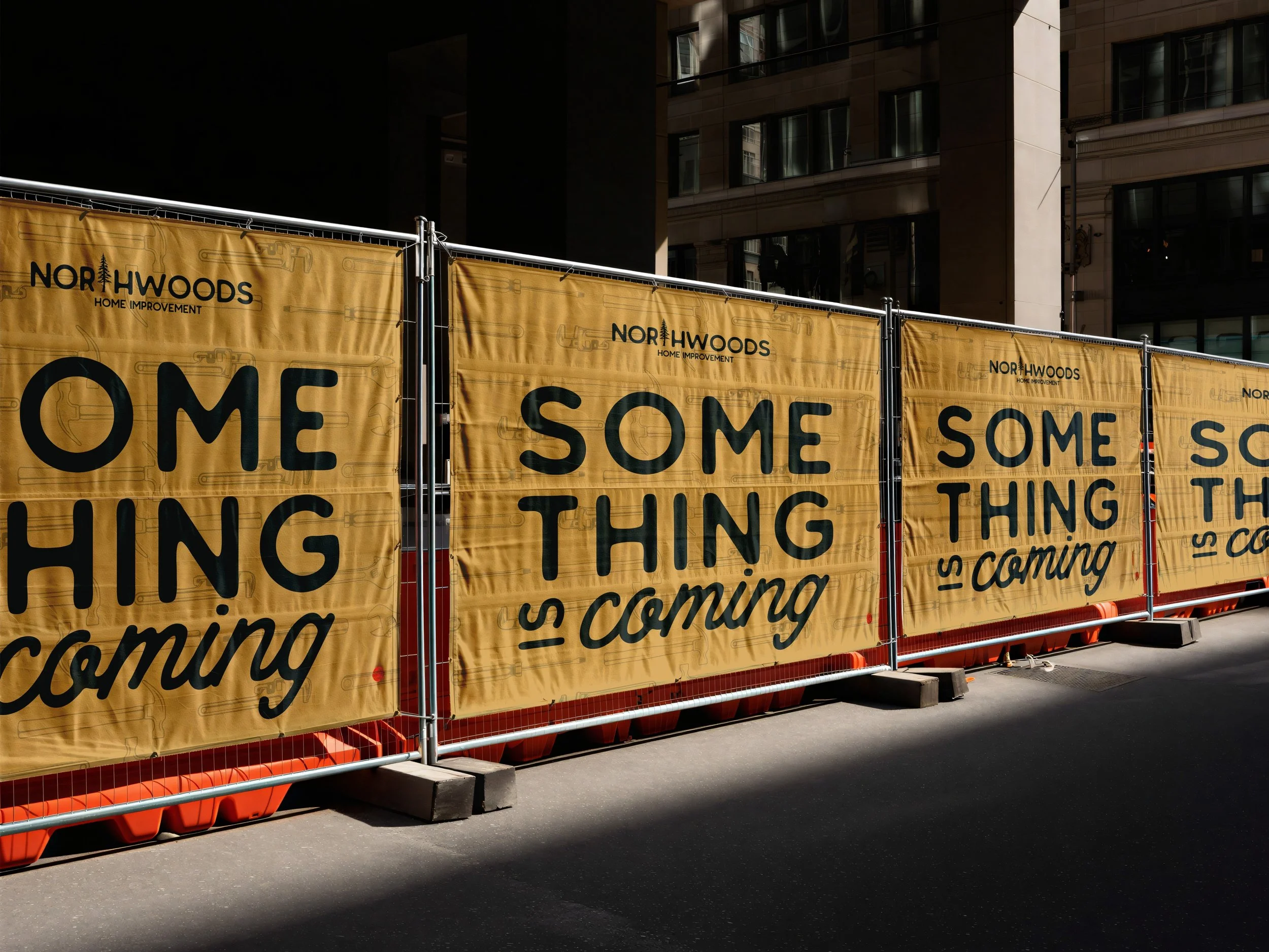 Yellow construction fencing with black text reading 'SOME THING IS coming' in large letters, placed along a city street with buildings in the background.