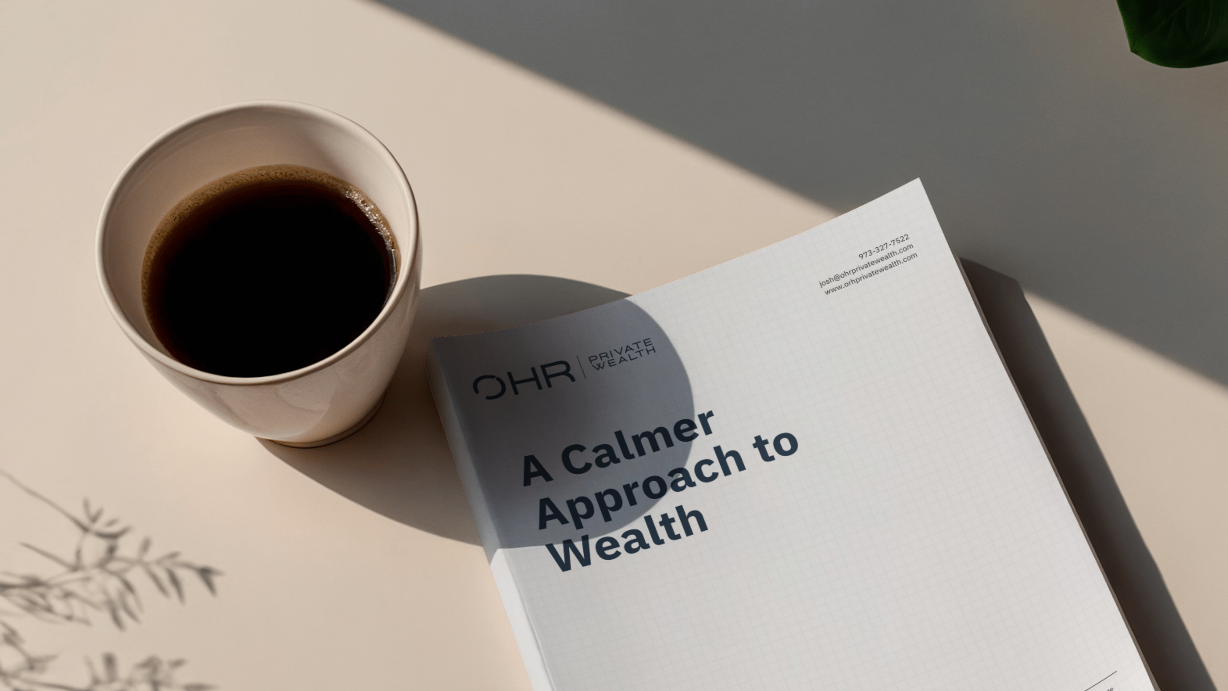 A white cup of black coffee and a booklet titled 'A Calmer Approach to Wealth' on a white surface with a shadow cast from the sunlight.