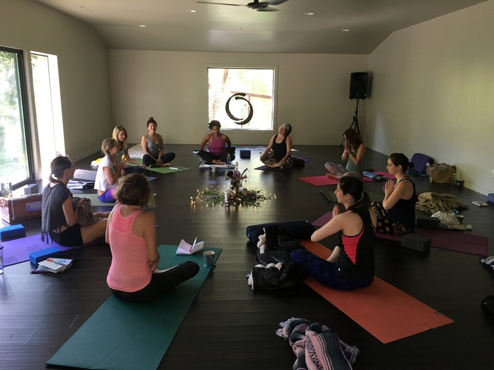 Attendees sitting on yoga mats in a yoga studio