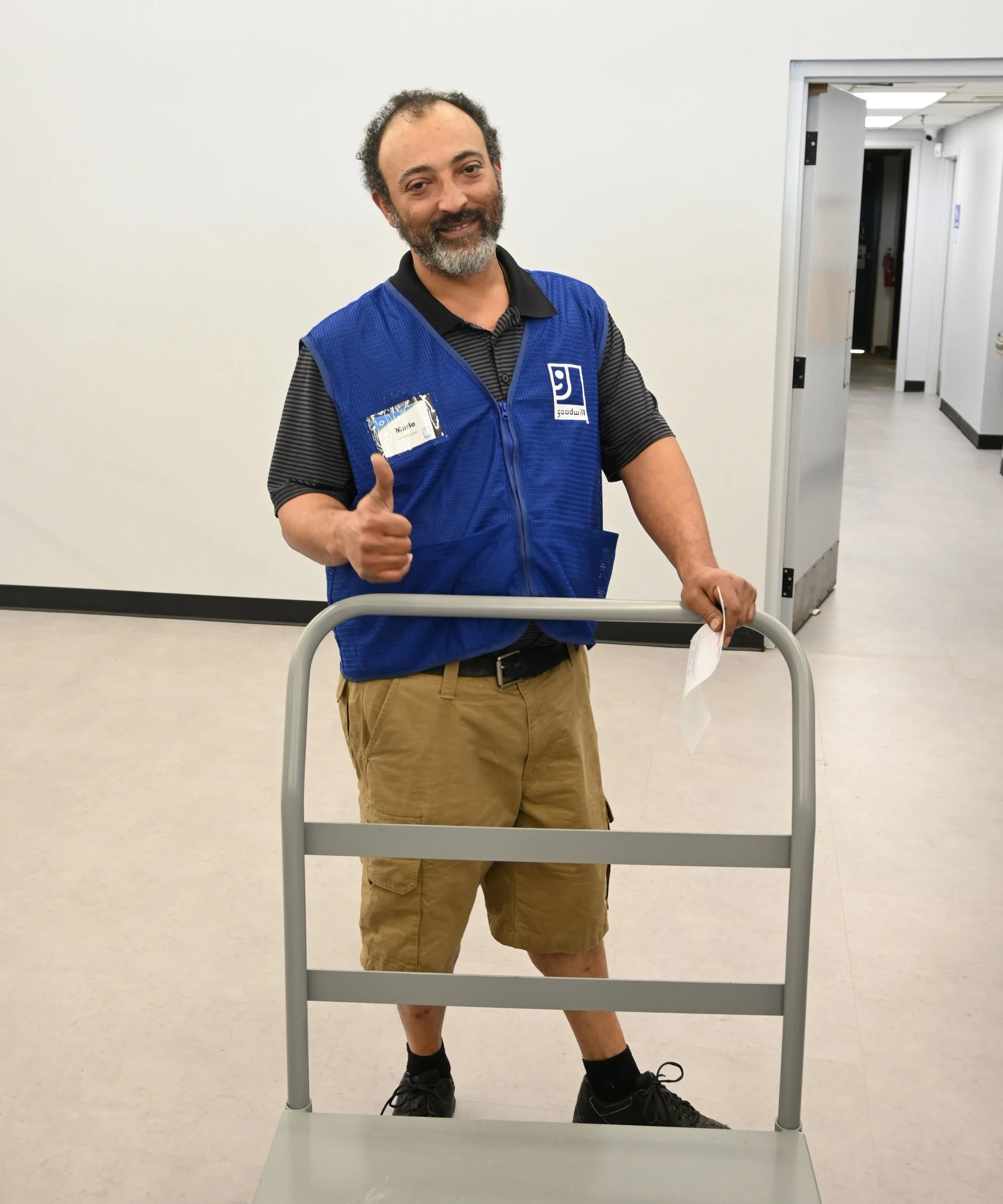 Goodwill worker, male smiling at the camera in blue vest