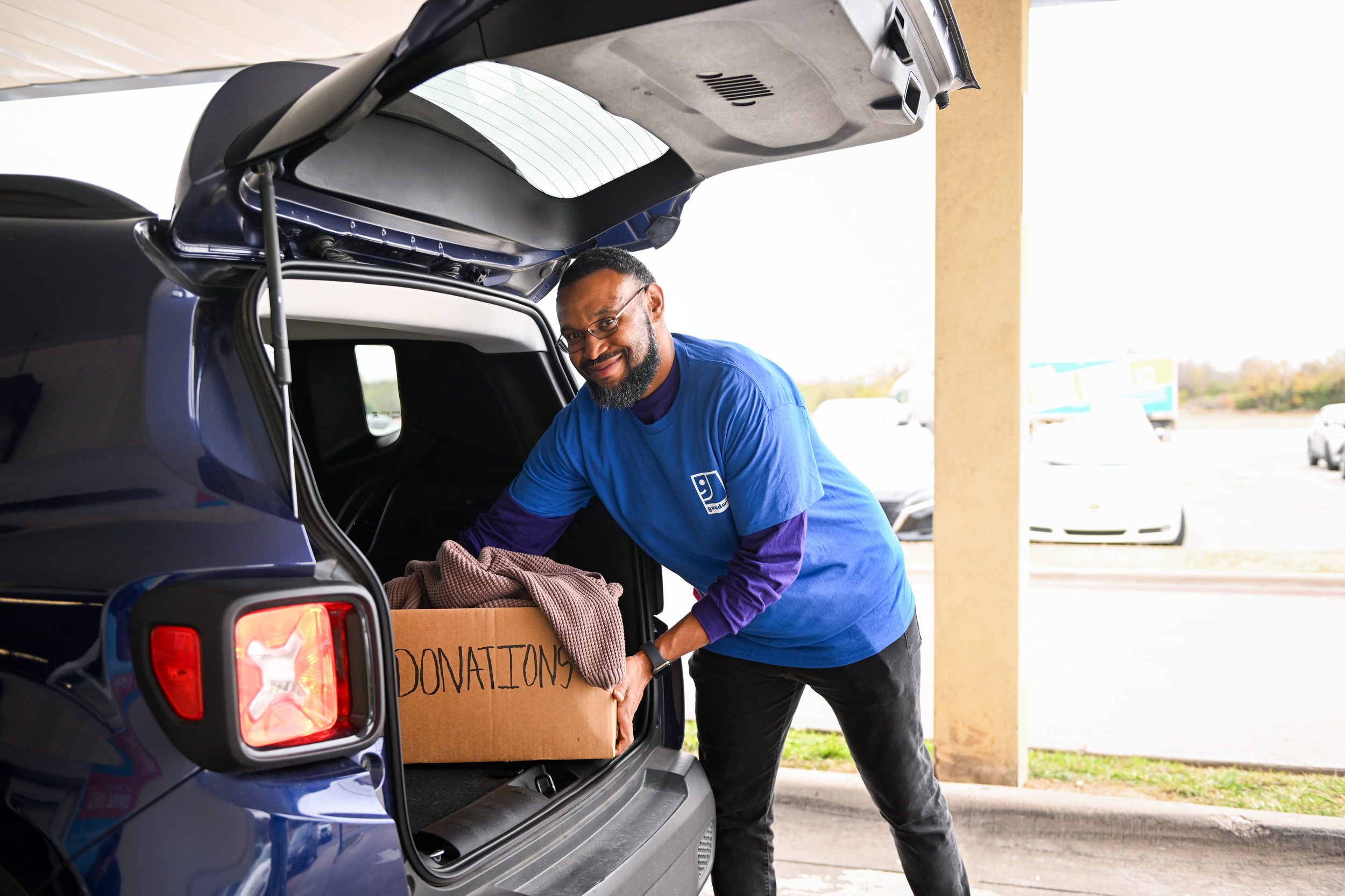 Goodwill employee unloading trunk of car donation