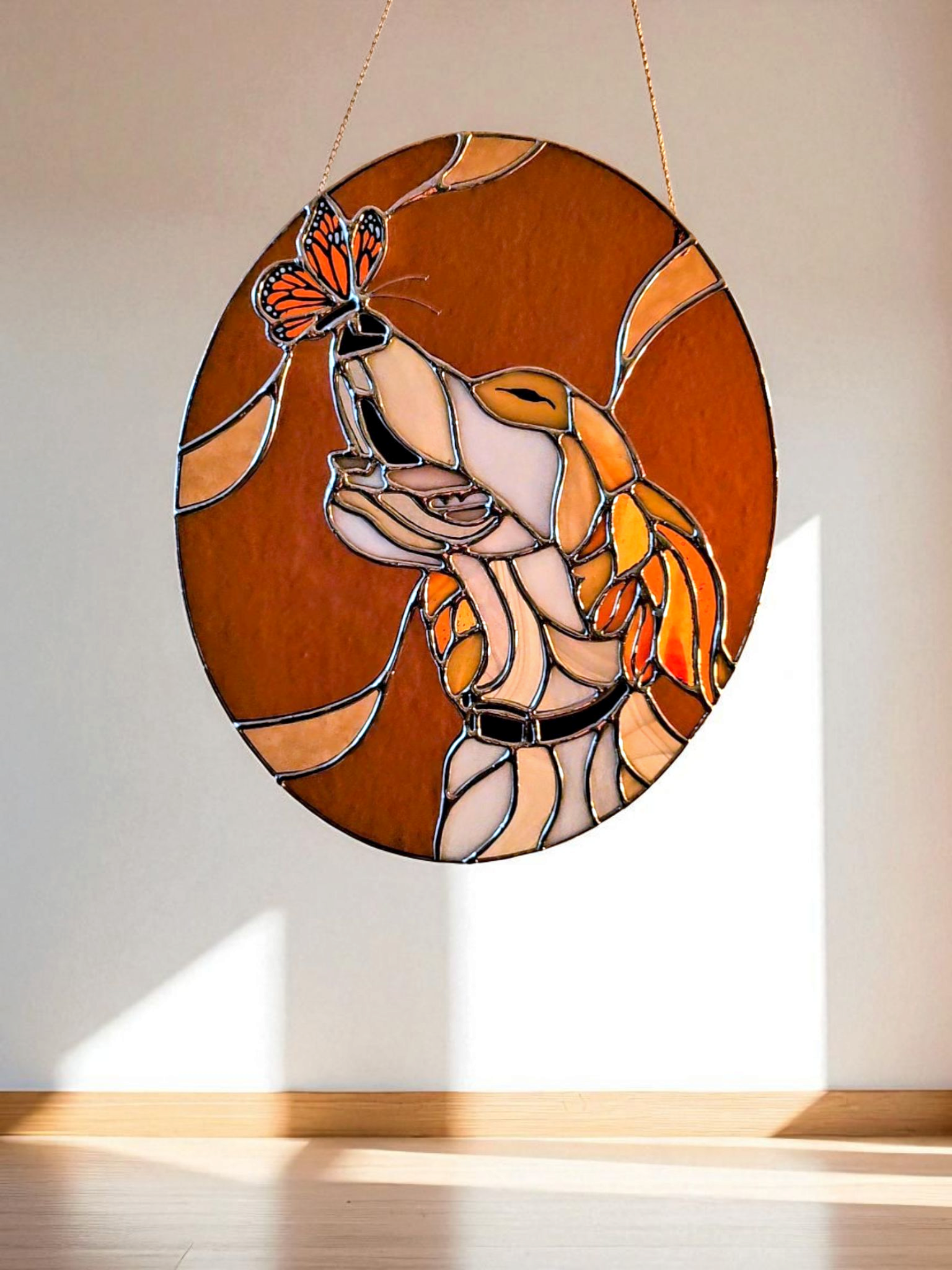 Stained glass hanging ornament depicting a dove with a monarch butterfly landing on its wing, set against a plain wall background.