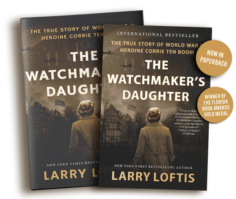 Two copies of the book "The Watchmaker's Daughter" by Larry Loftis featuring a cover with a woman in a coat standing in front of houses and a cloudy sky, with gold circle badges indicating "Now in Paperback" and "Winner of the Florida Book Awards Gold Medal."