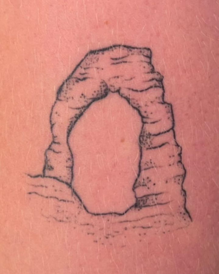 Tattoo of a rock formation resembling an arch, with the word "Healed" written below.