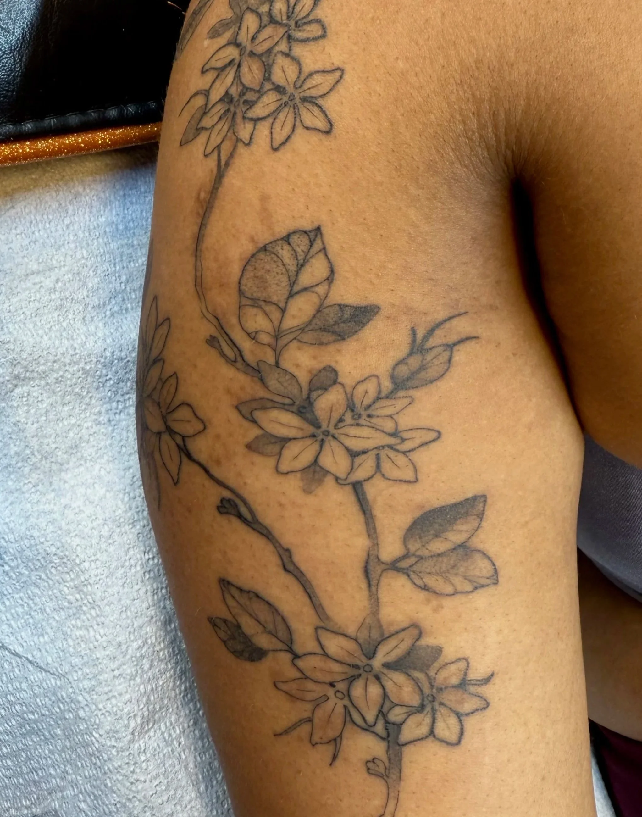 Outline tattoo of flowers and leaves on a person's upper thigh