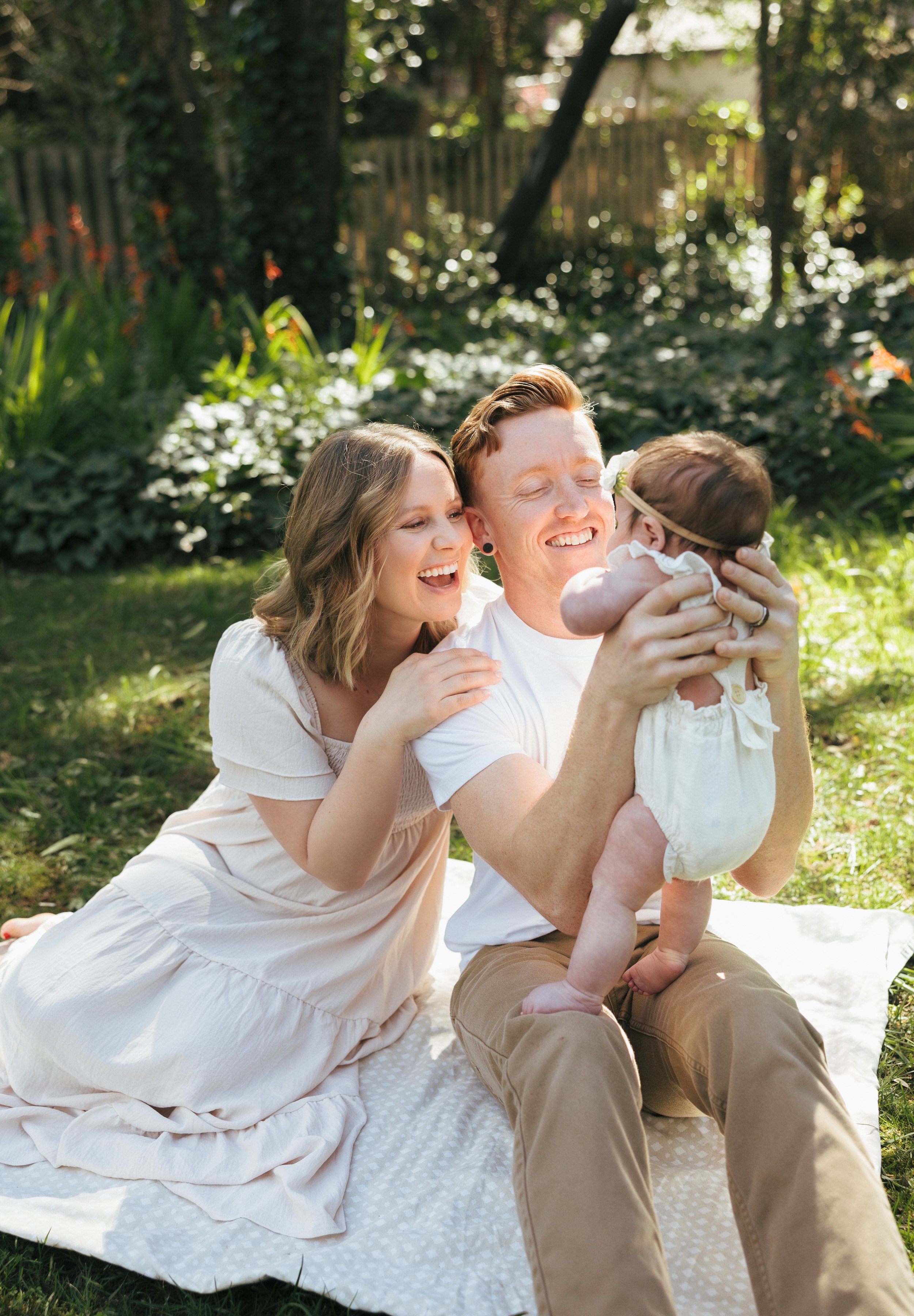 A husband and wife joyfully smiling at their baby during their family photos in Auburn California
