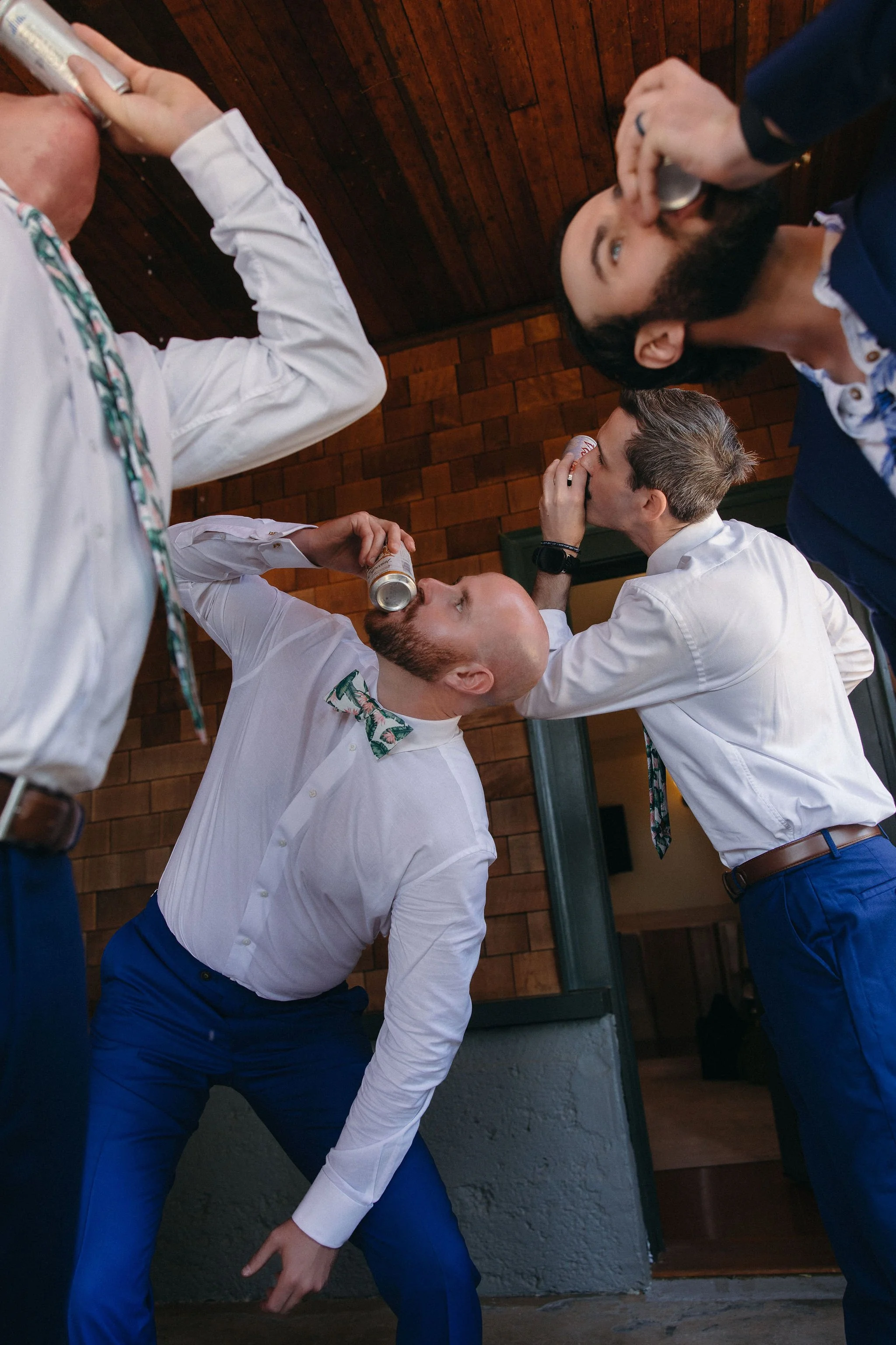 Group of men in formal attire drinking and socializing indoors with wooden walls.