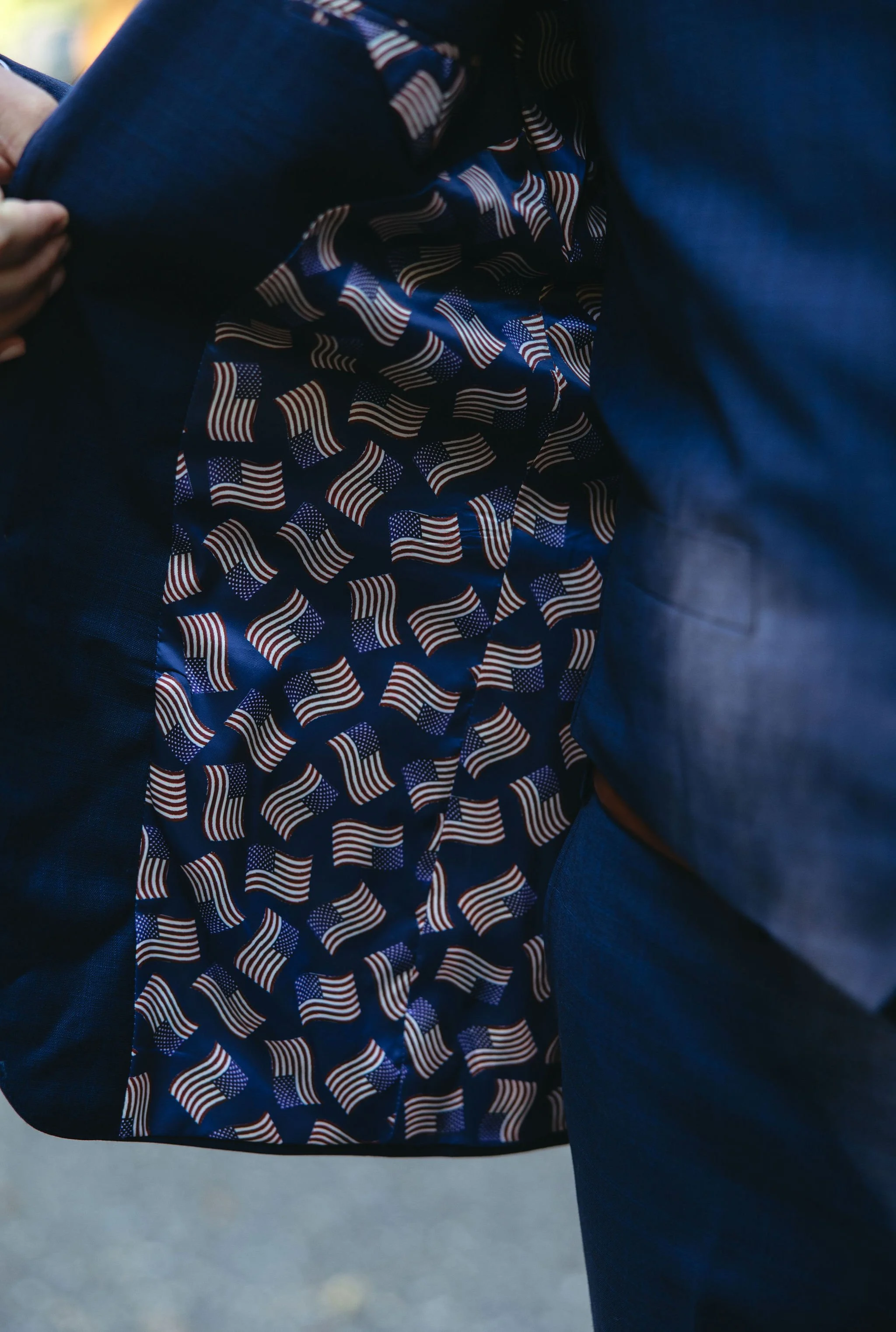 Close-up of a person wearing a blue suit with a lining of small American flags on the inner side of the jacket.
