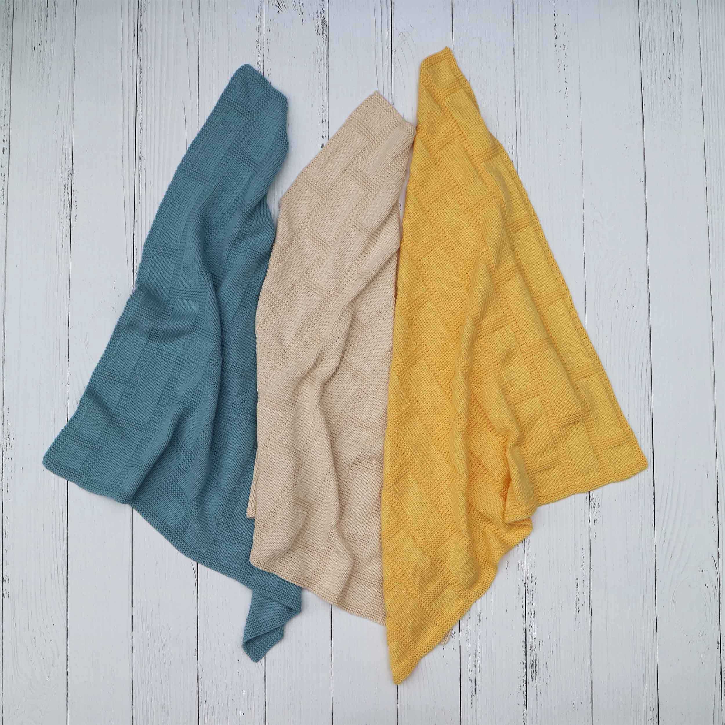 Three colourways of the latticework blanket in blue, yellow and cream.