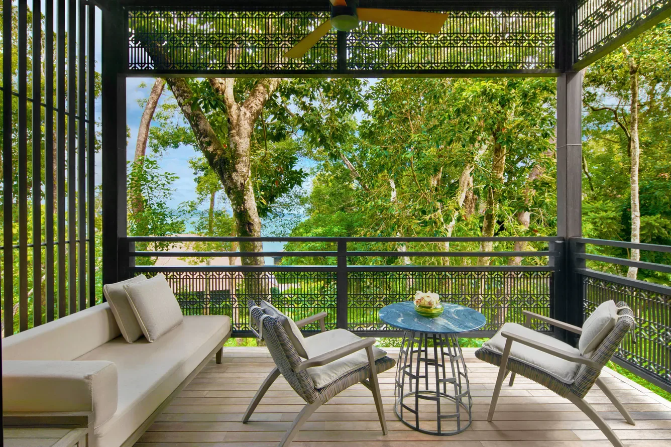 terrace with furniture and rainforest view with glimpses of the sea beyond