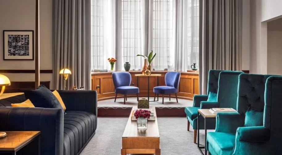 Interior of a suite at the Kimpton Clocktower in Manchester decorated in contemporary classic style with a large bay window and sofas