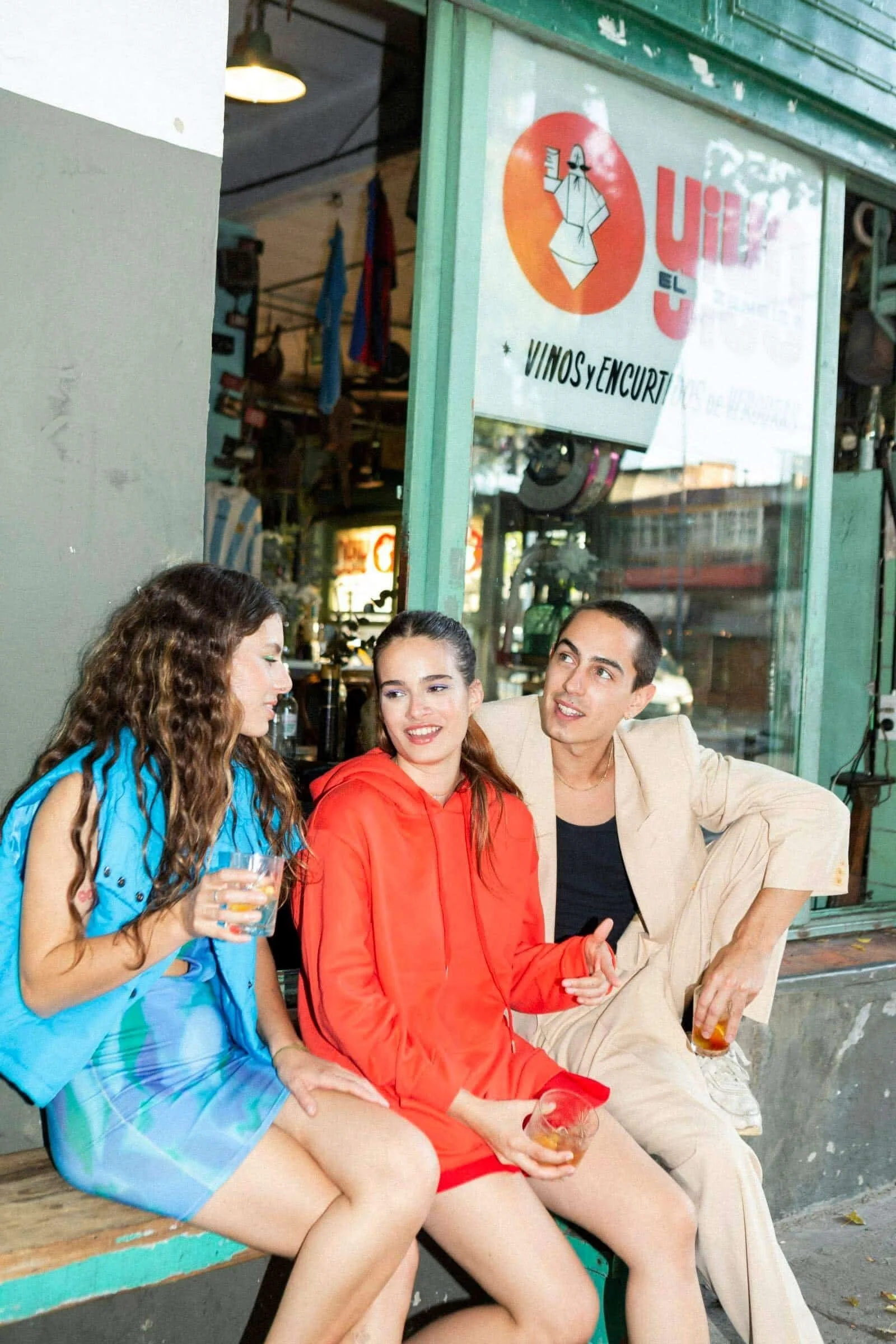 Photo of three people sitting outside a shop