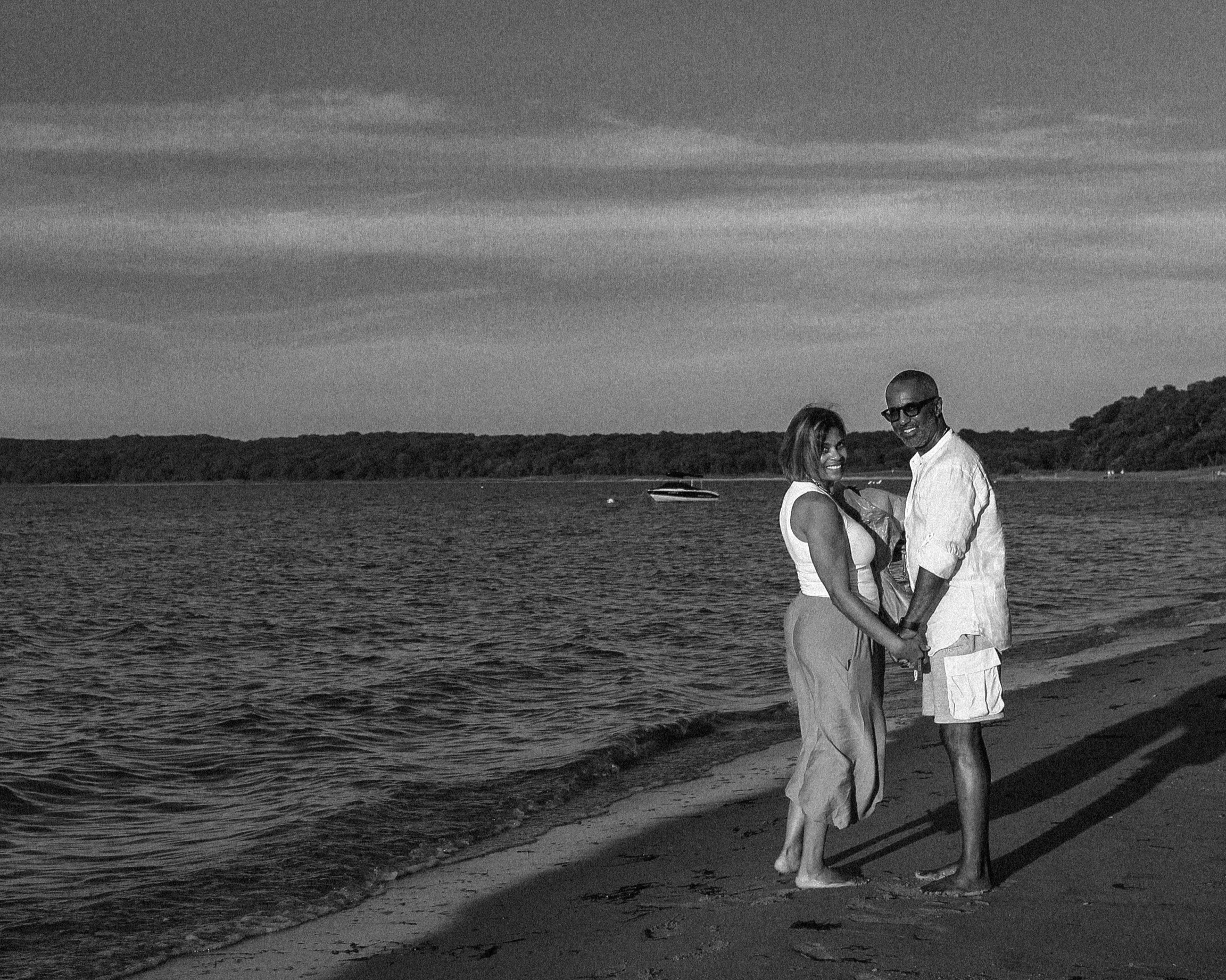 Newly engaged couple laughing and celebrating beside the water at Azurest Beach