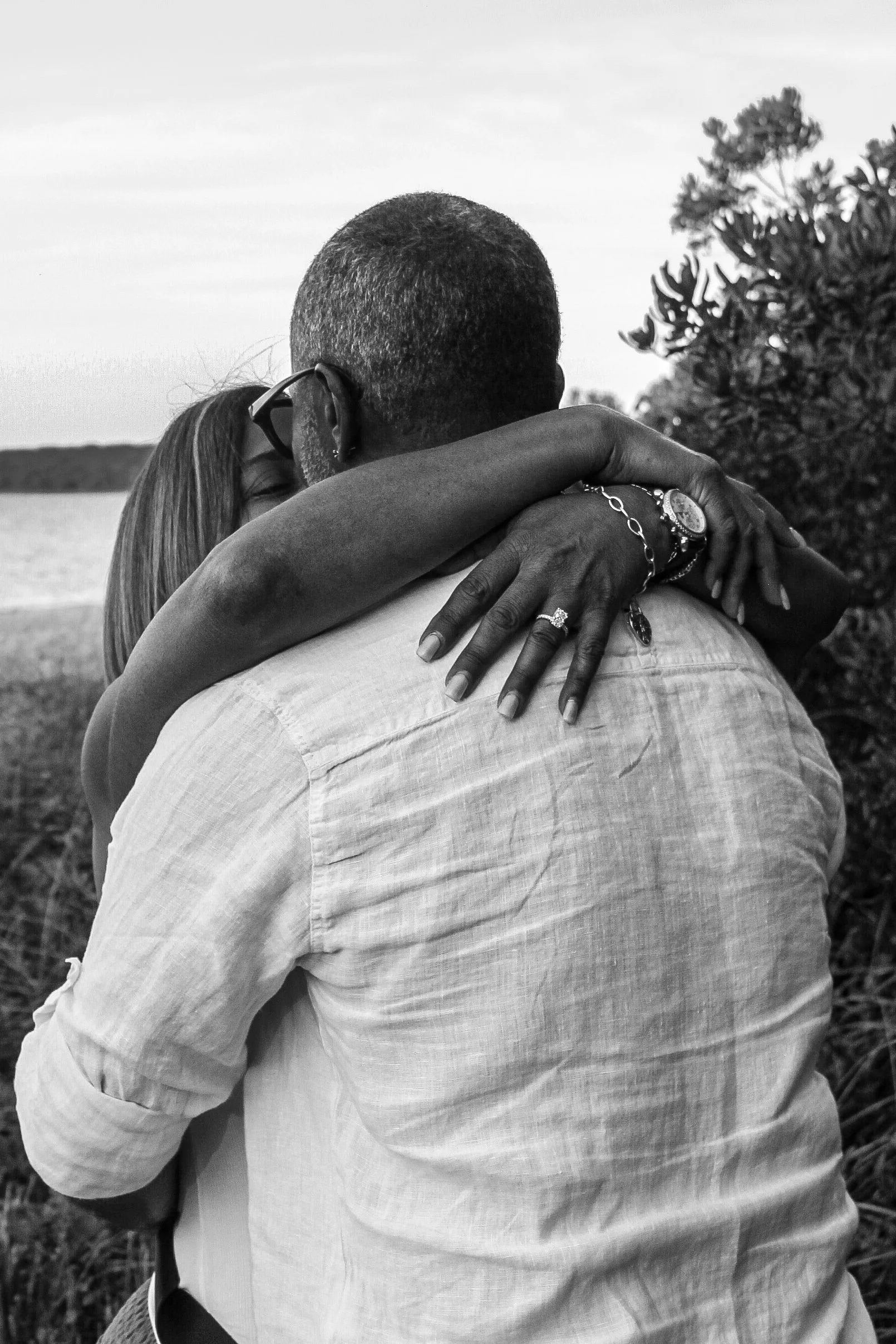 Black-and-white portrait of Henry kissing Deborah’s forehead beside the rose-stem pathway