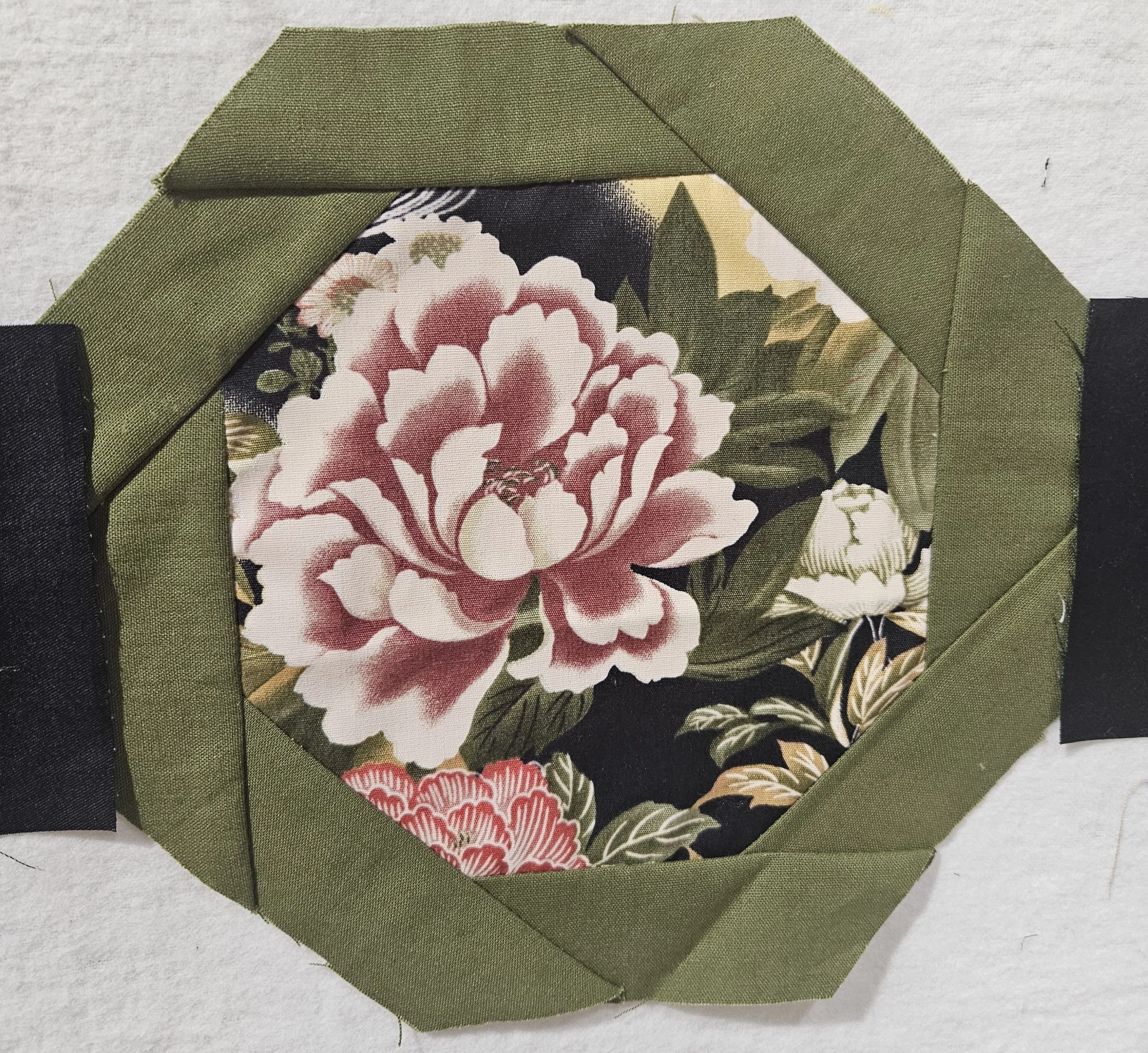 A block consisting of a floral fabric with pink flowers octagon surrounded by green fabric