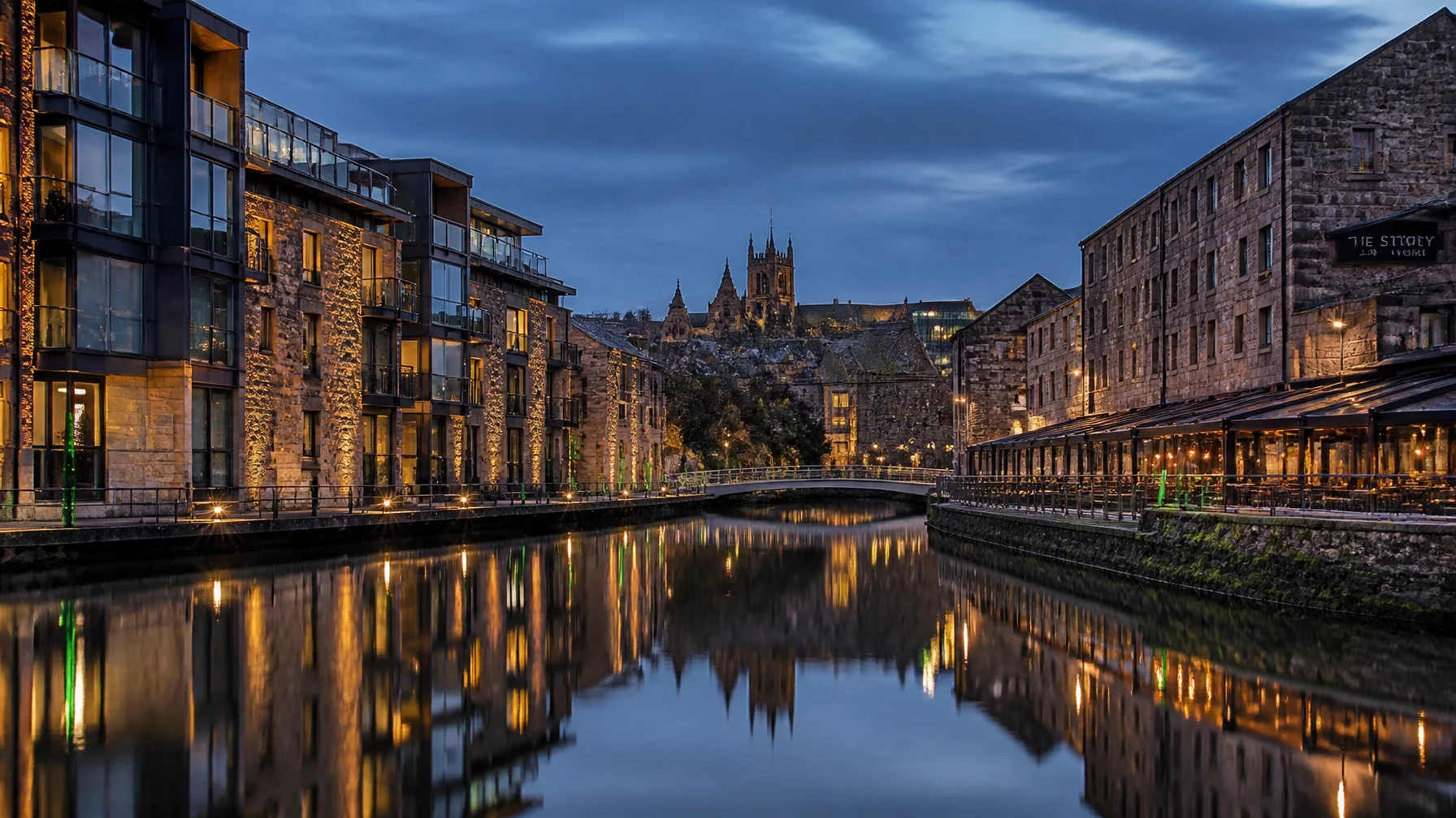 Brick buildings along the river in Lancaster with a Cathedral in the background