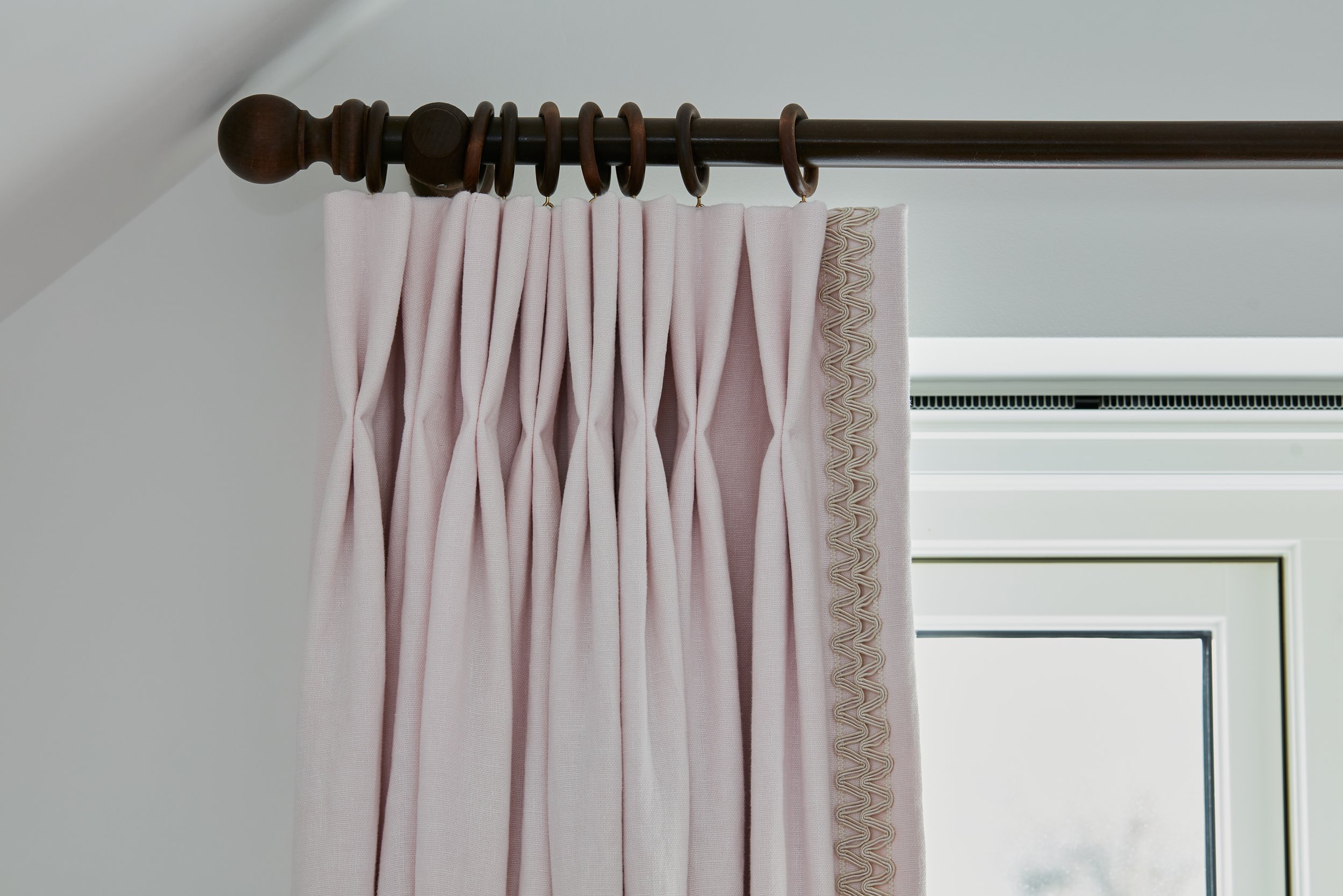 close up of pink curtains on a dark wood pole