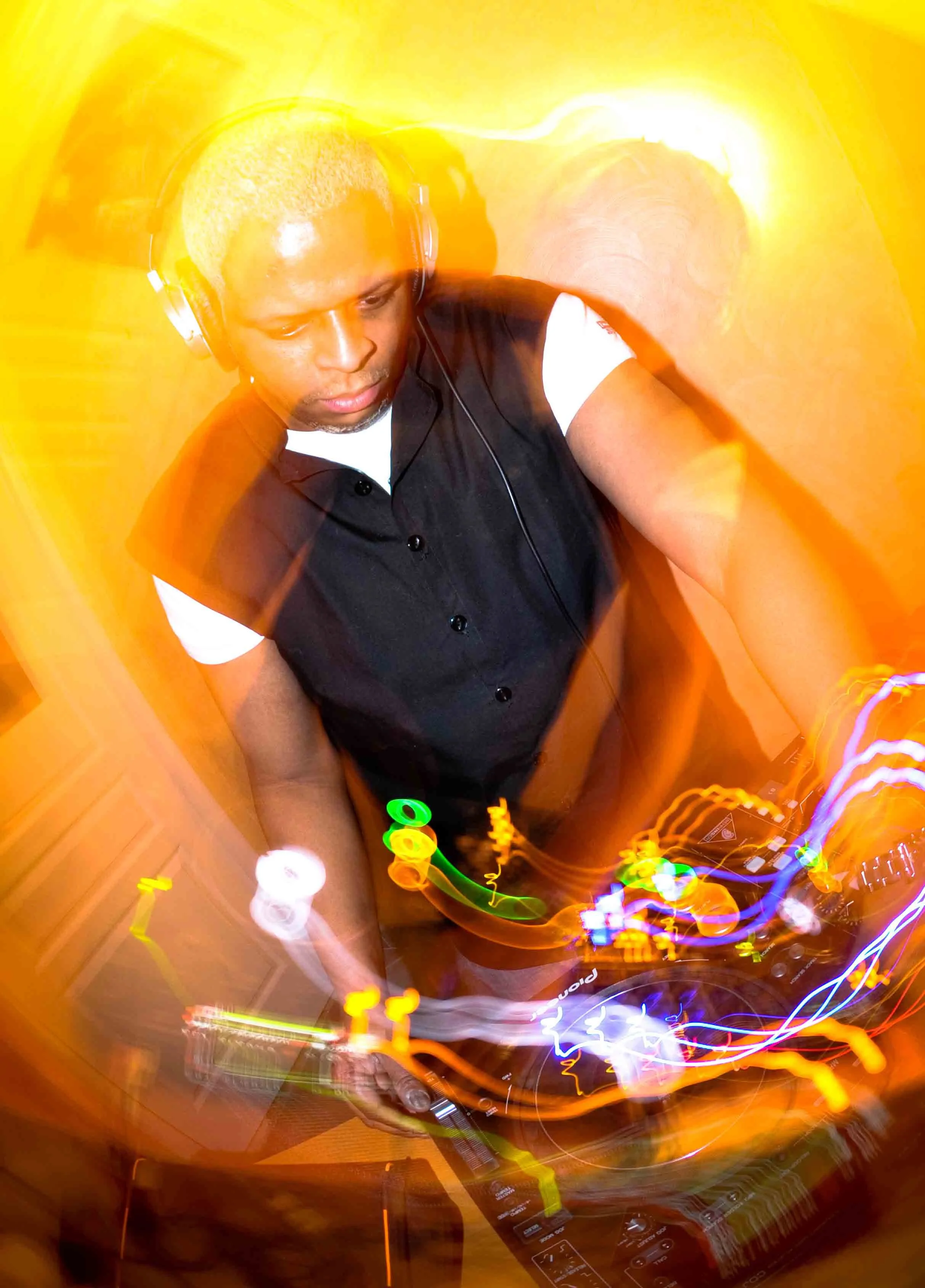 Un disc-jockey joueur avec casque, manipulant un équipement DJ, entouré de lumières colorées en mouvement dans une ambiance de fête.