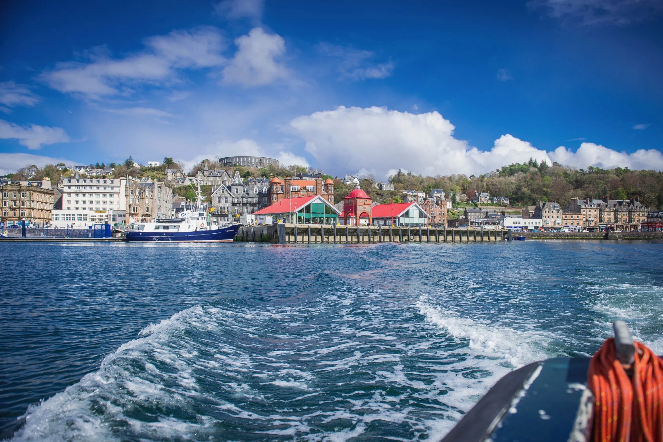 View of a harbor with boats and a town in the background, taken from the water during daytime.