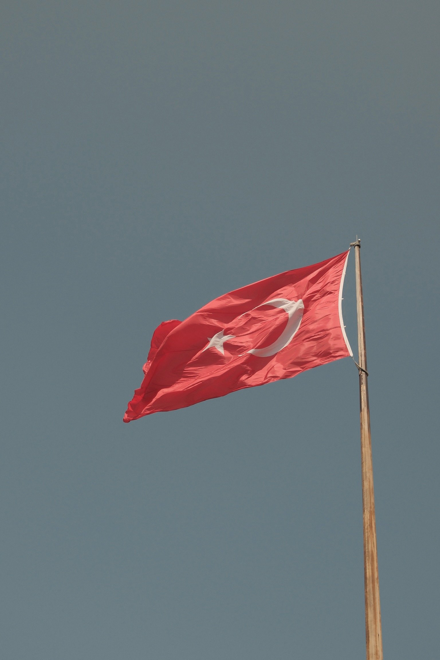 Türkische Flagge weht im Wind vor einem blauen Himmel.