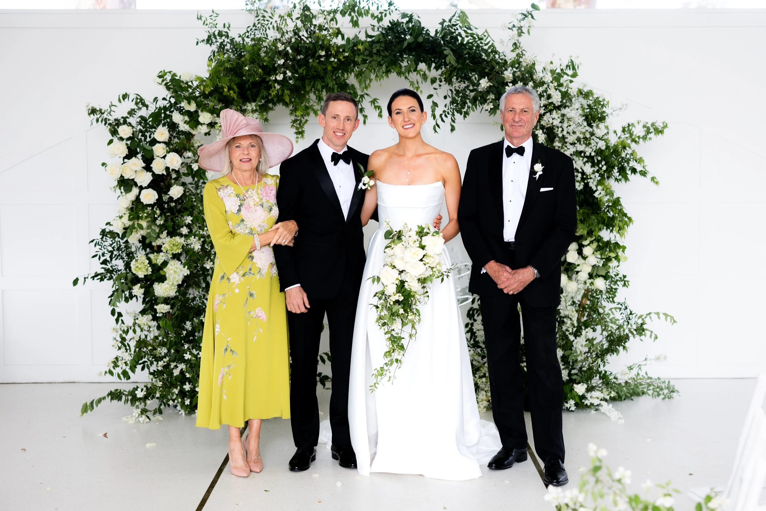 A woman adjusting a man's bowtie on a balcony with city buildings in the background.