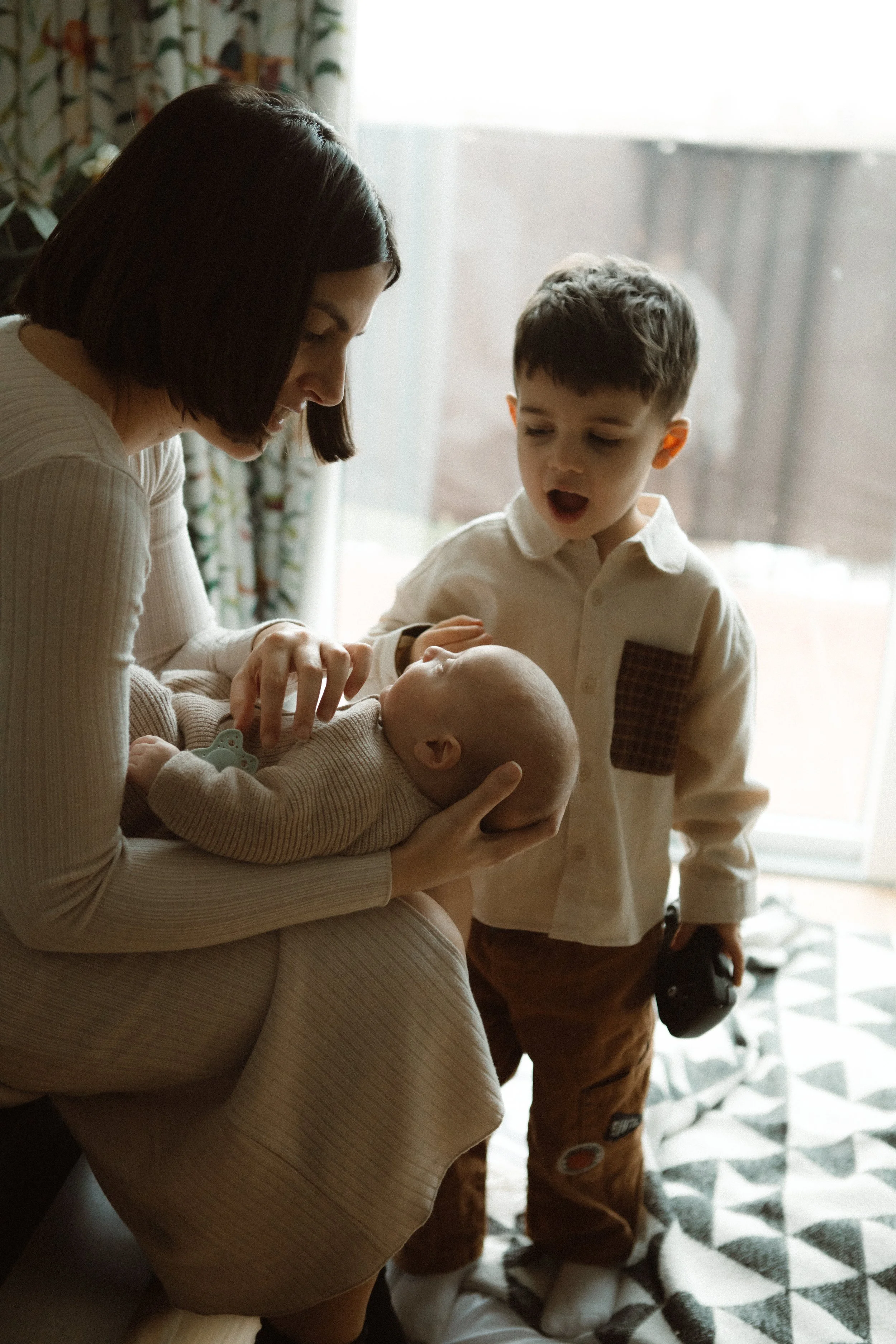 Mother with newborn baby and child during in-home family session, Southeast London