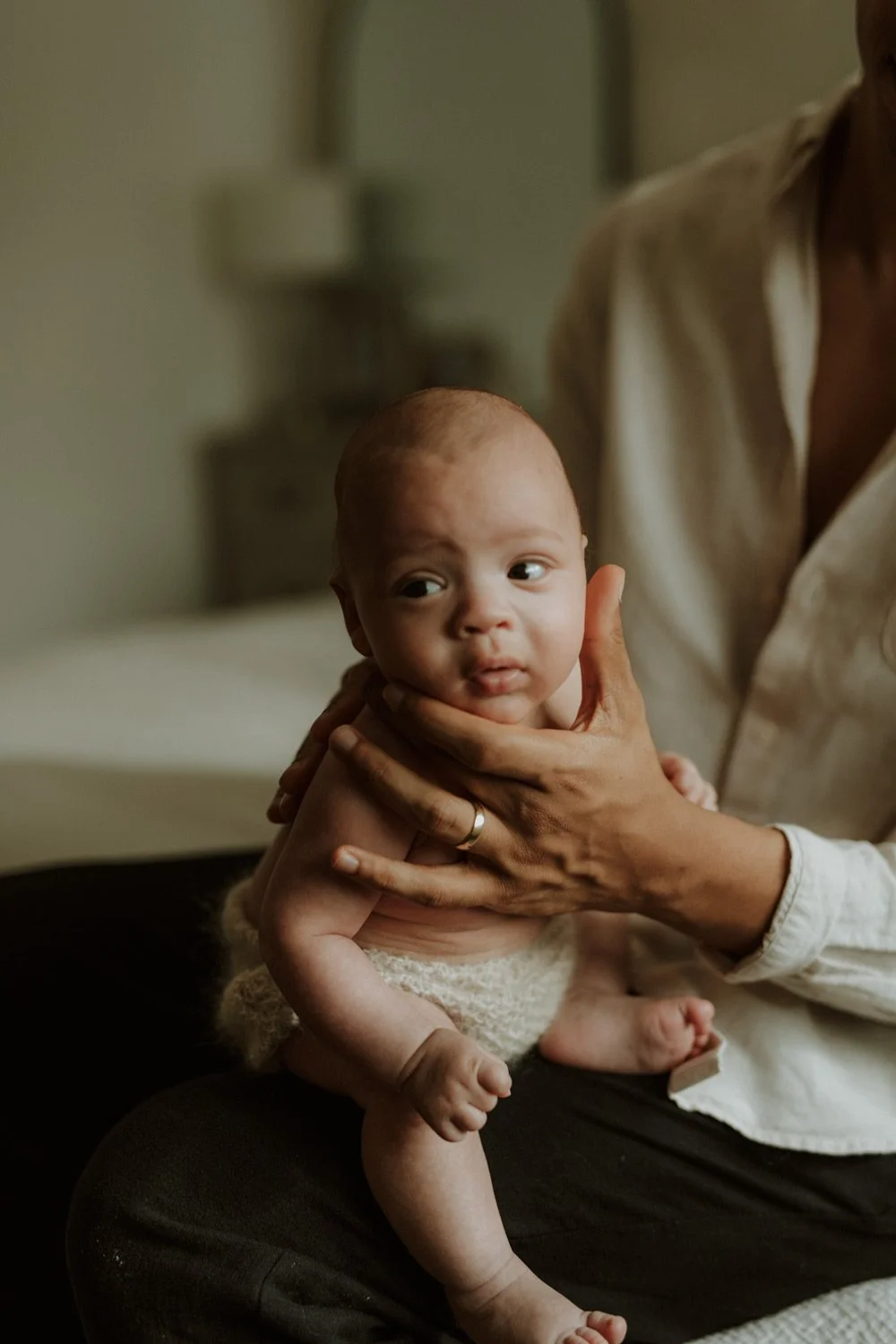 Newborn baby being gently burped by their father, in soft natural light at home