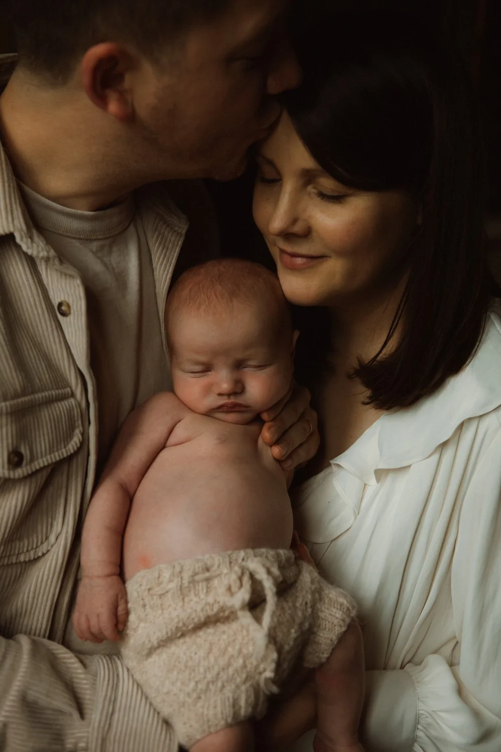 Mother and father holding their newborn close