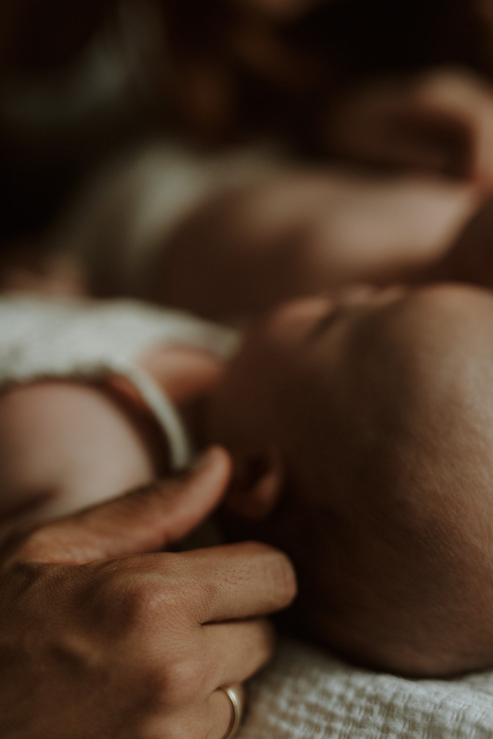 Close-up of a father’s hand resting protectively on his newborn baby, capturing a tender, intimate detail