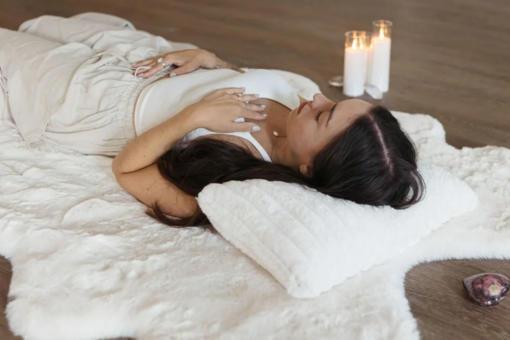 Woman resting on a white blanket with her hands on her chest.