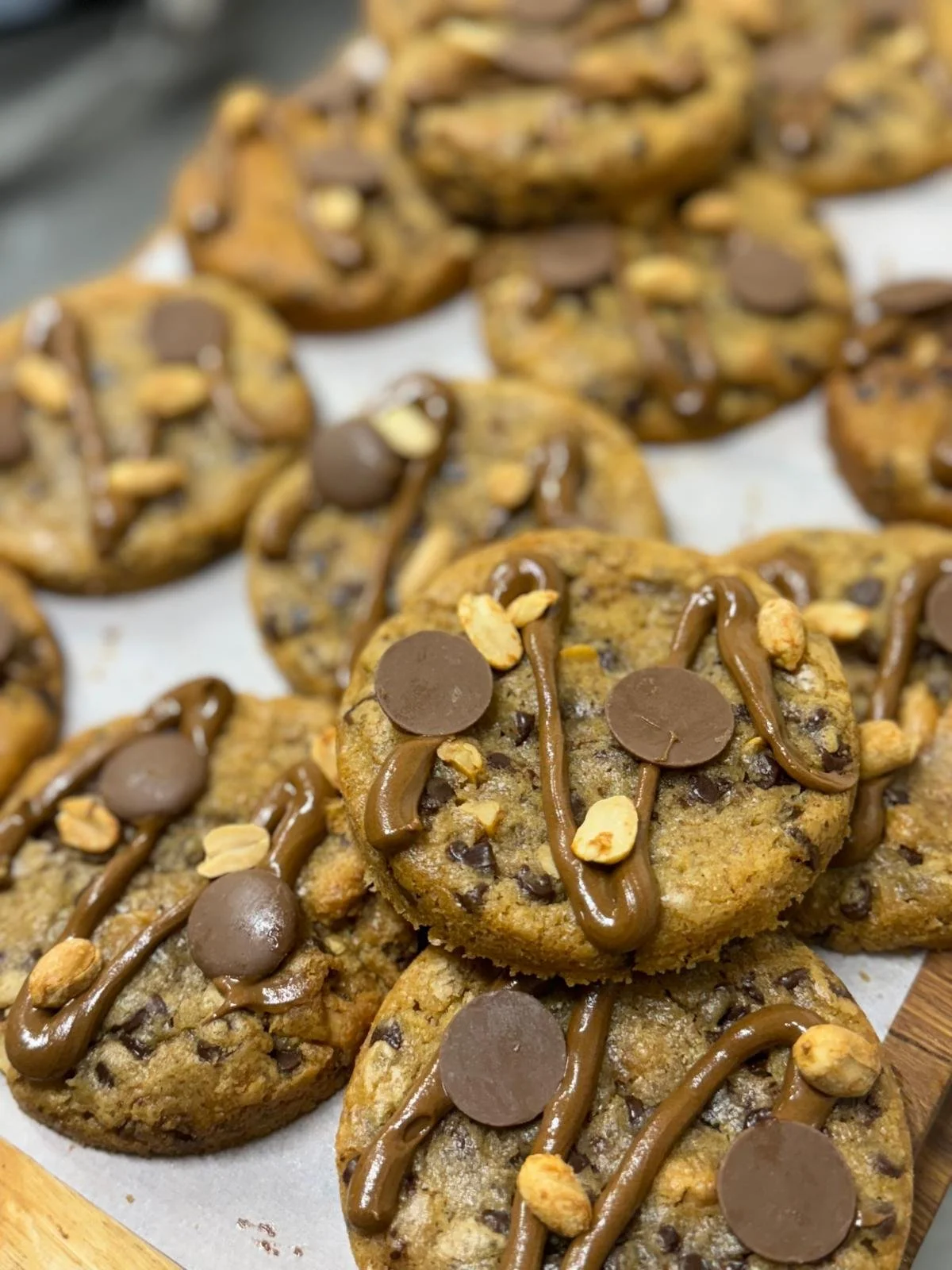 Cookies aux pépites de chocolat, décorés de sauce au chocolat, de pépites de chocolat et de noix.