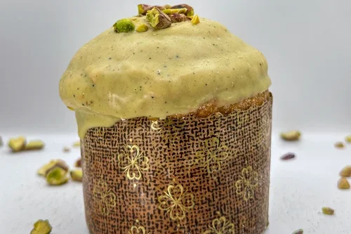 Gâteau de Noël avec glaçage vert, pistaches et décor floral doré.