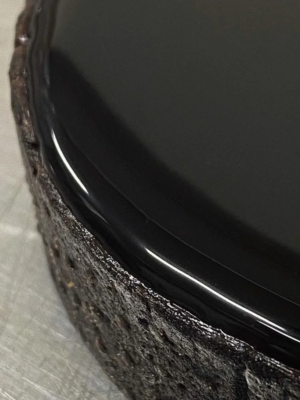 Détail d'une assiette noire posé sur une assiette en céramique défectueuse.