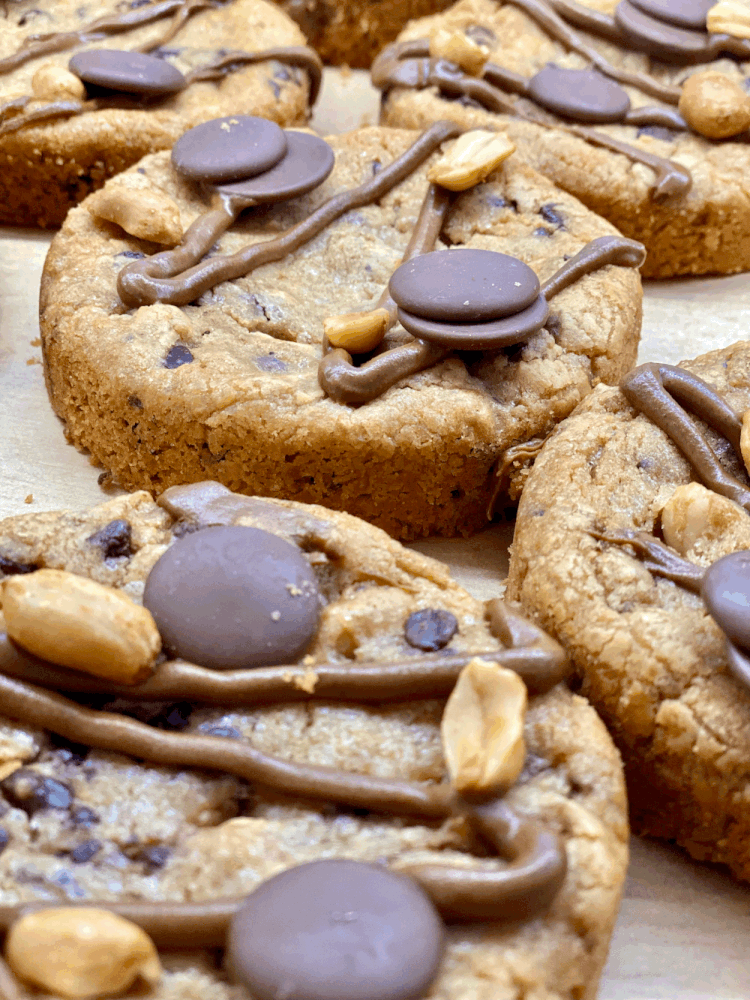Cookies aux pépites de chocolat décorés de chocolat fondu, de cacahuètes et de pépites de chocolat.