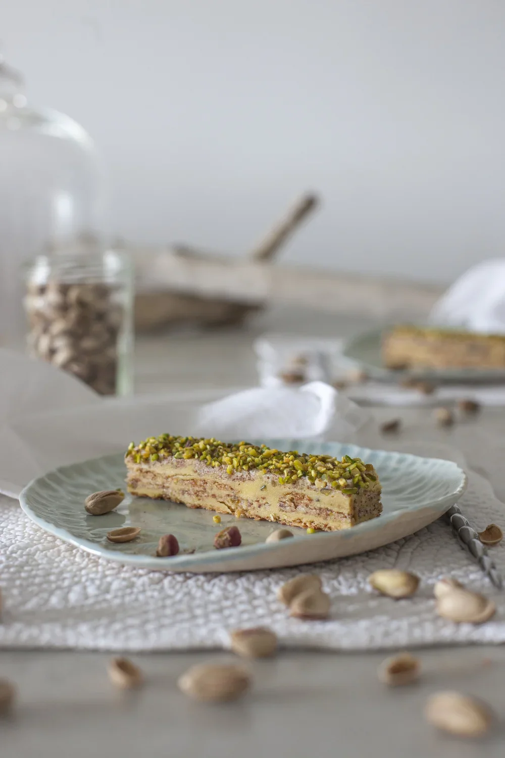 Une part de tarte au pistache avec des pistaches entières, sur une assiette