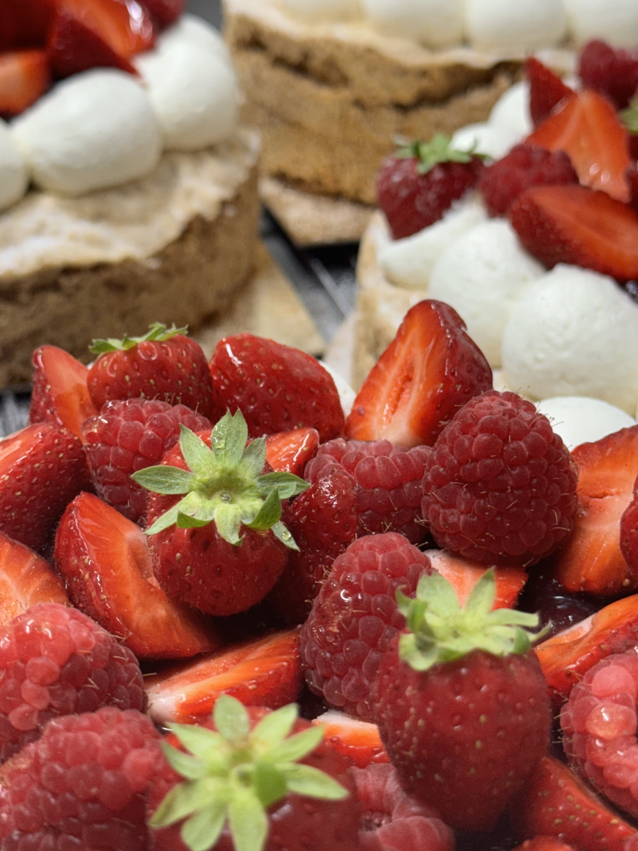 Fraises, framboises, etmelon en dessert décoratif, avec des parts de gâteau en arrière-plan
