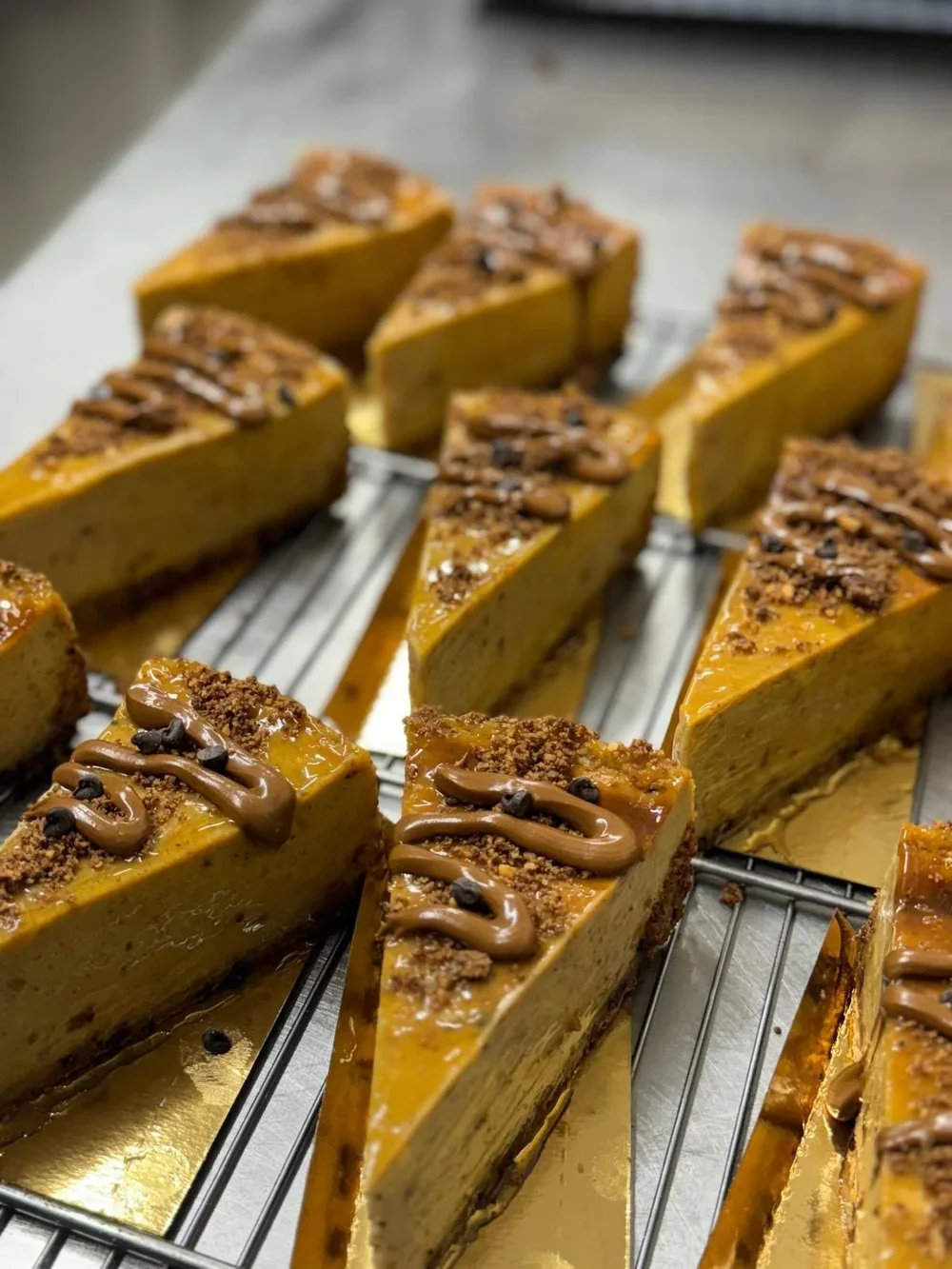 Tranches de cheesecake au caramel décorées de morceaux de chocolat et d'un filet de chocolat fondu