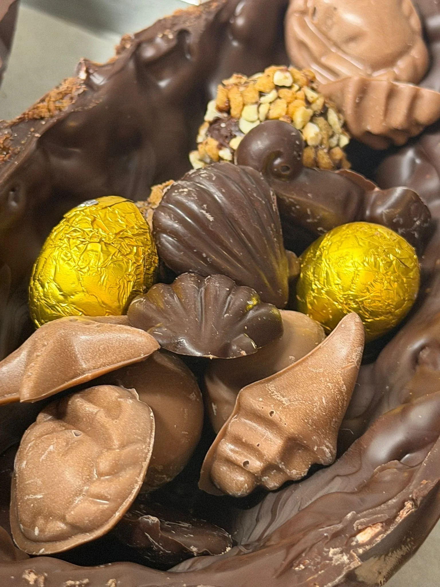 Un assortiment de chocolats, avec des œufs en chocolat dorés, des truffes, et diverses formes en chocolat