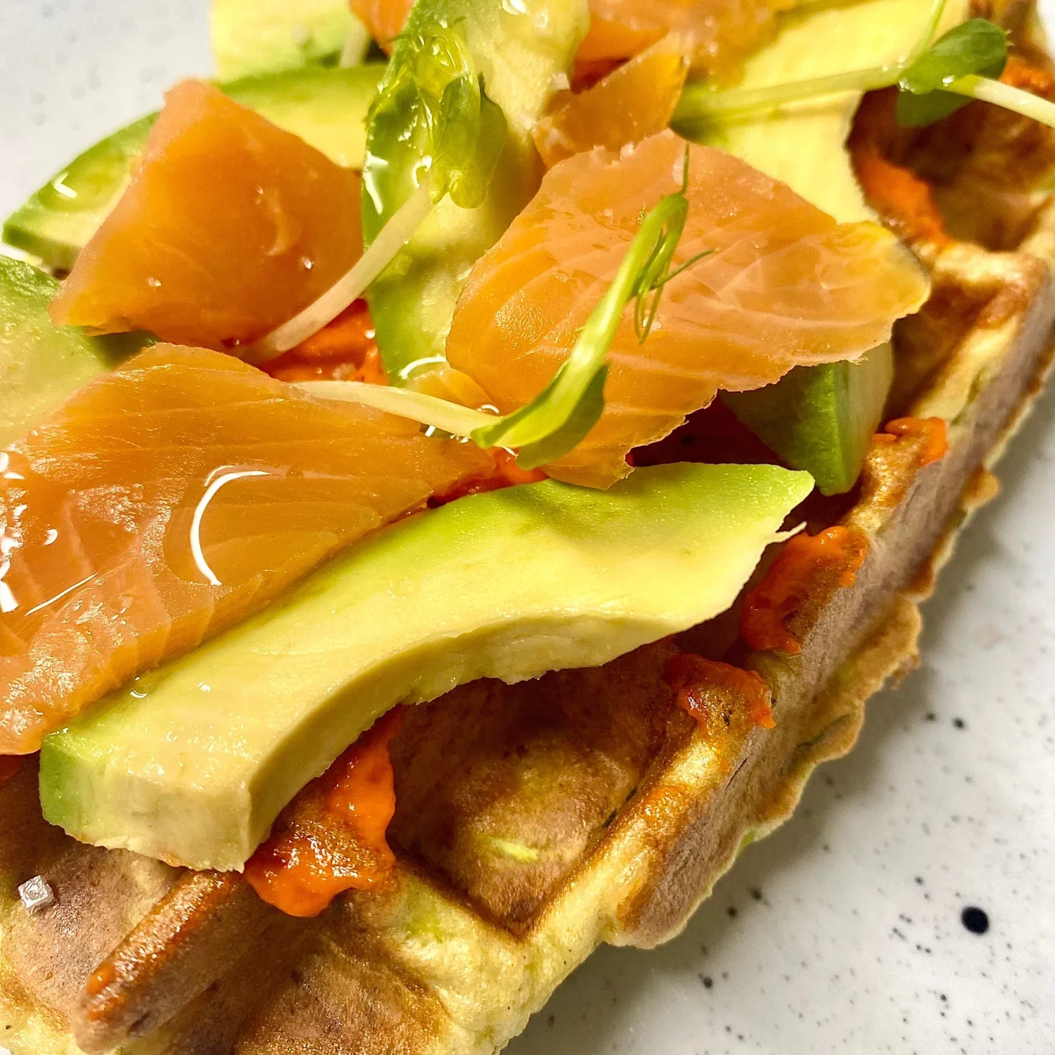 Gaufre garnie de saumon, avocat, concombre et microgreens.