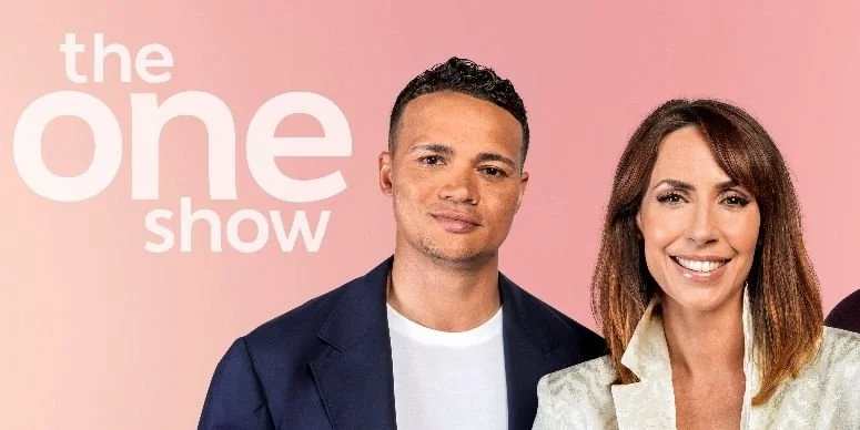 Photograph of two smiling TV hosts, a man in a navy blazer and a woman in a light-colored blazer, against a pink background with the text 'the one show' in large white letters.