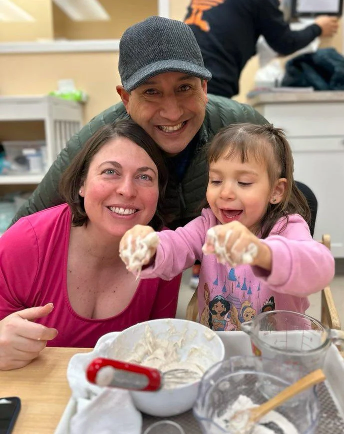 A mom, dad, and their daughter playing with mushy goo  and smiling at Orange Seeds Montessori Centre