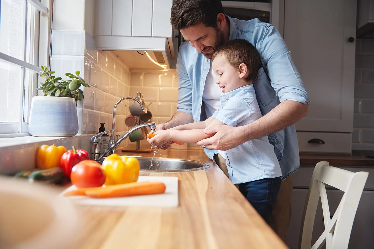Father and son washing carrots at the kitchen sink | Orange Seeds Montessori Centre