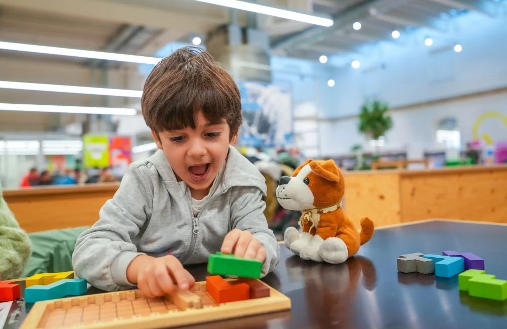 A young boy putting toy blocks together in a Montessori classroom with confidence | Orange Seeds Montessori Centre