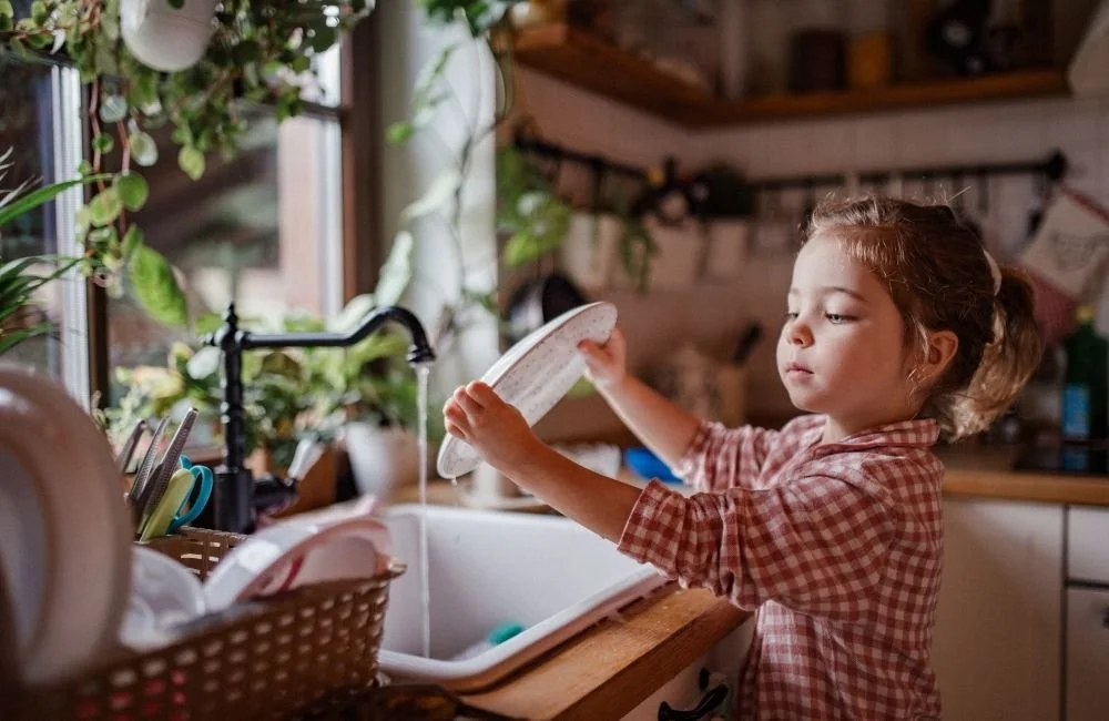 A little girl doing dishes at home by herself