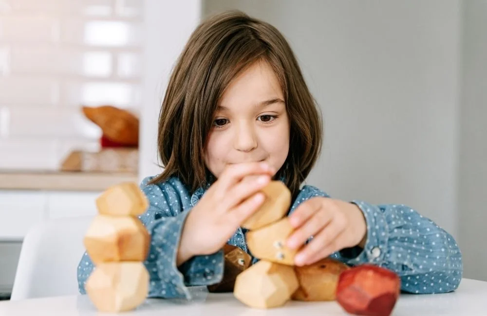 A little girl plying with weirdly shaped wooden blocks