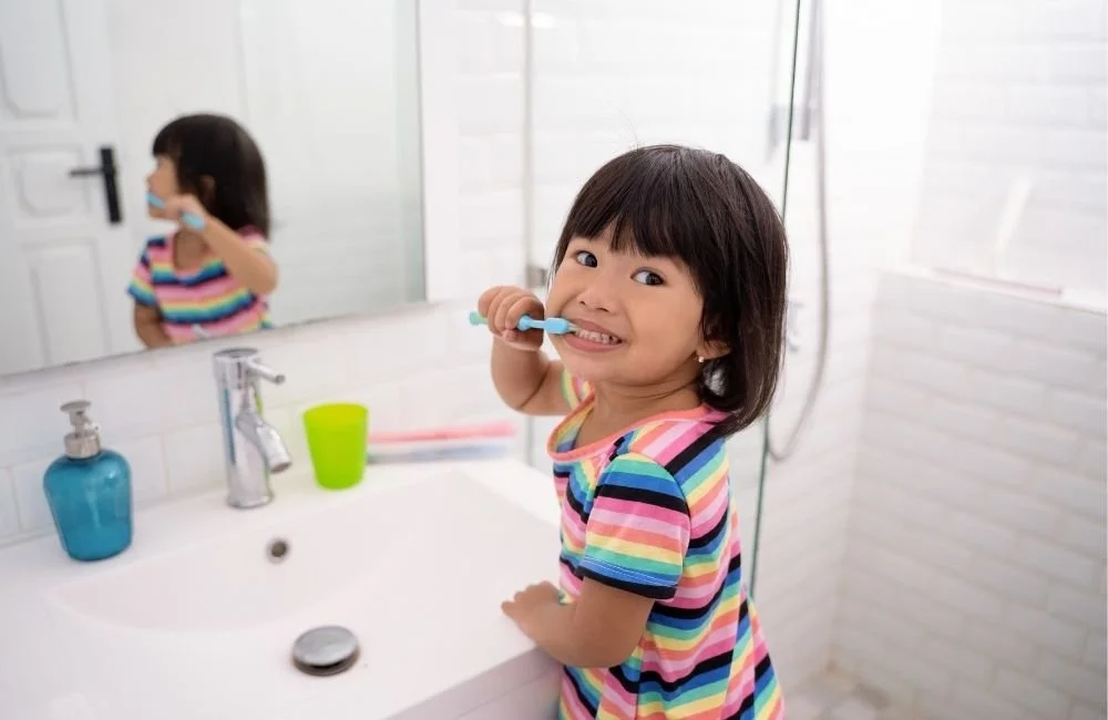 A little girl brushing her own teeth at home