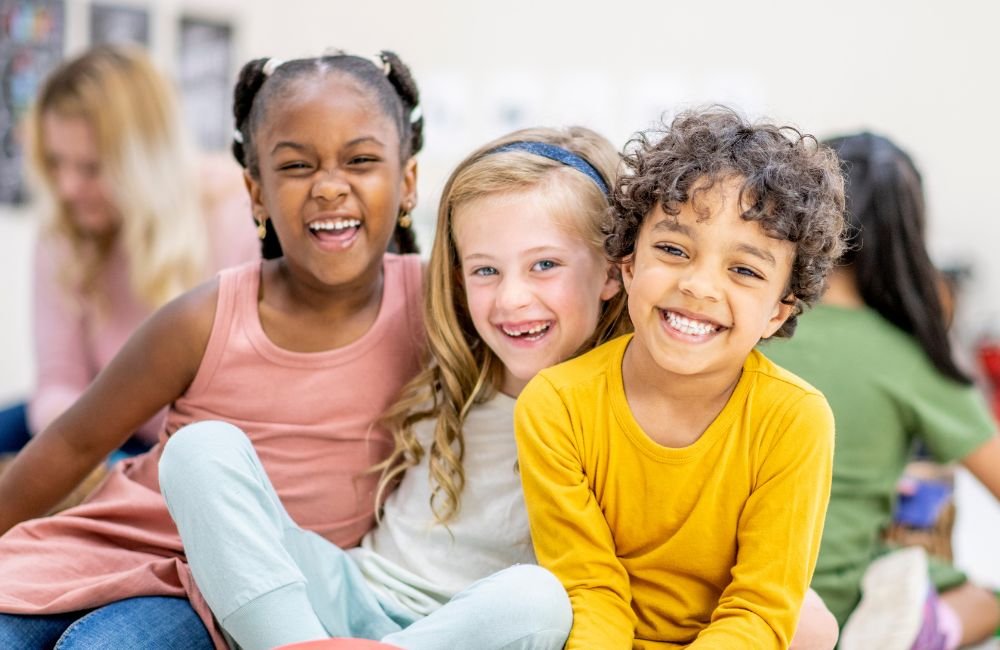 2 girls and a boy smiling in a classroom | Orange Seeds Montessori Centre