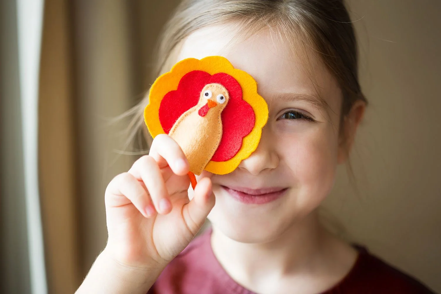 Little girl holding a turkey finger puppet up to her face and smiling | Orange Seeds Montessori Centre